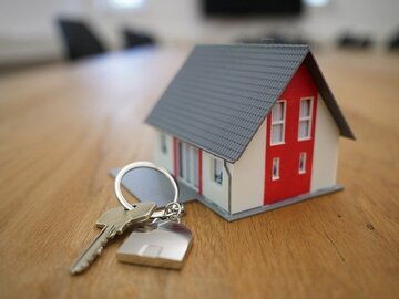 Maqueta de una casa sobre una mesa al lado de una llave en representación de la Evolución precios del alquiler