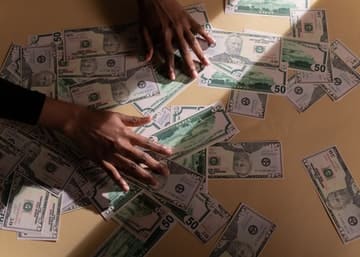 Manos con muchos billetes sobre una mesa representando nuestra página de  Reconocimiento de deuda